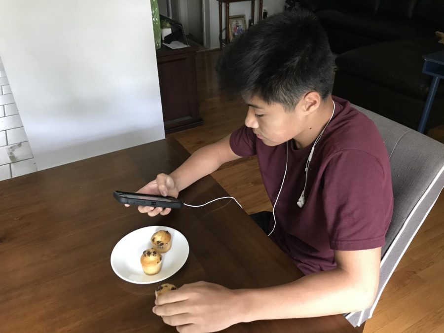 Sophomore Nick Kim on Sept. 9 eats lunch the same way he does at school: ready to listen to music and on his phone. After he eats his lunch he goes outside to see his friends. Photo by Sean Kim.