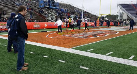 Ryan Stevens a media relations volunteer watches the Senior Bowl practice as part of his job.