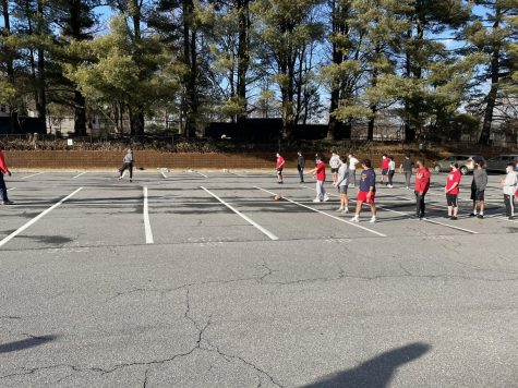 The football team practices plays in the parking lot on Mar. 1.