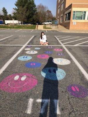 Senior Erin Chang admires her parking spot with chalk-drawn smiley faces on Apr. 7.