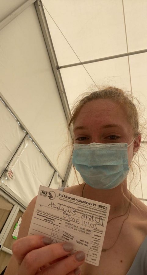 Junior Lizzie Nelson holds her vaccination card after receiving her first Covid vaccine dose.