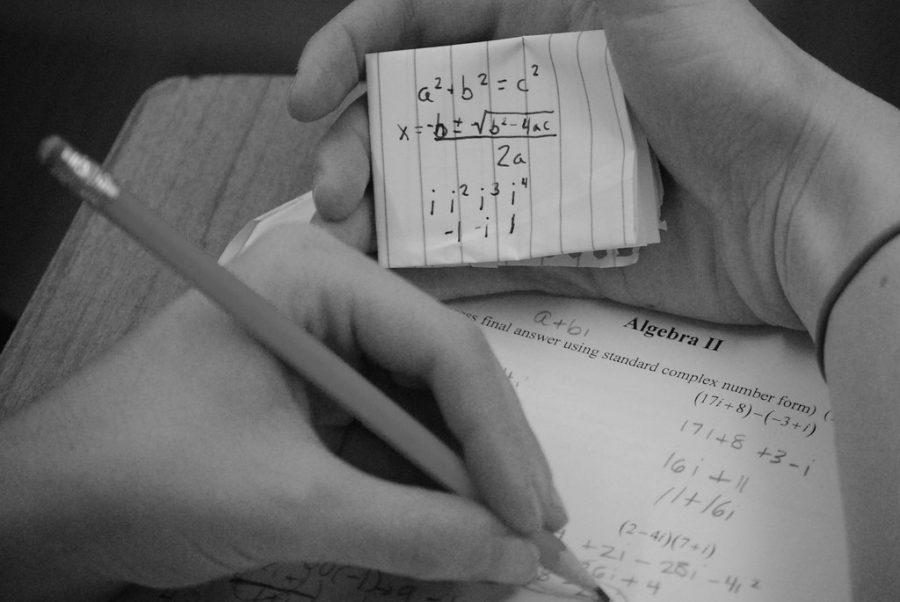 A student completes a math test using a hidden formula paper.