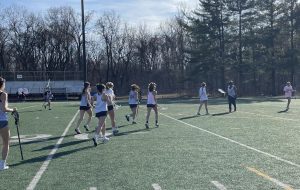The JV lacrosse girls run over to their goalie to congratulate her after a great game.