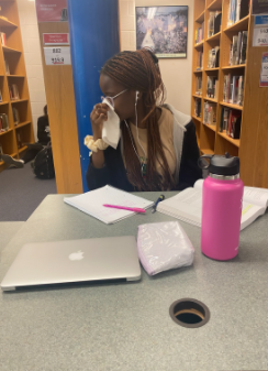 Sophomore Georgina Kaddu blows her nose is in the library during lunch. Allergy season is my least favorite season because it makes my eyes and nose itchy, Kaddu said.