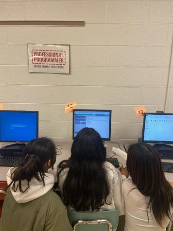 Sophomore girls gather around a computer, collaboratively learning code in AP Computer Science.