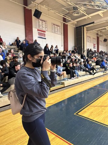 Junior Gurnoor Sohdi takes pictures during Senior Night for boys basketball on Feb. 13.  Sohdi set her schedule to take pictures during each game, boys and girls, working around the court through all the chaos of the game. “Taking photos has been a challenge. It’s gotten much better with practice. People say practice makes perfect so its been a learning experience for me,” Sohdi said.