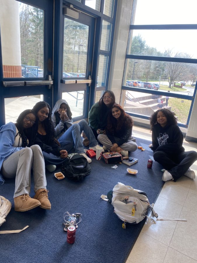 Sophomores Teemo Taiwo, Destinee Sousani, Brigette Gomez, Daniela Bunuan, Maddy Mathew, and Jade Claude sit in the front of the school building during lunchtime. I love this time of the day because we get to all be together and just relax,  Sousani said.