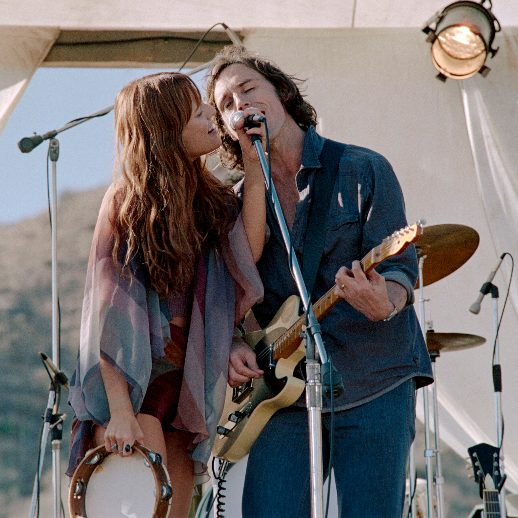 Lead singers Daisy Jones (Riley Keough) and Billy Dunne (Sam Claflin) perform together in the Amazon Prime miniseries Daisy Jones & the Six.
