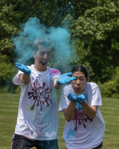 Junior Nico Dorazio and sophomore Emma Yuan throw powder at color run participants on May 19.