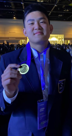 Junior John Wang poses with his medal after winning second place in the buying and merchandise competition at the Decathlon International Conference.