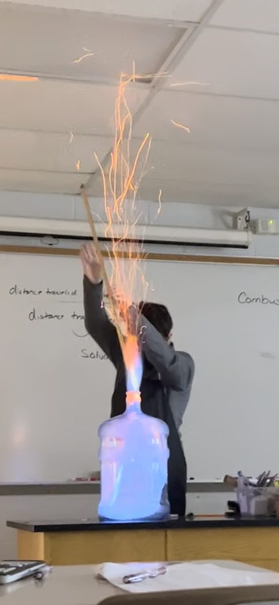 AP+Chemistry+teacher+Brett+Bentley+uses+a+student+assistant+to+demonstrate+a+combustion+reaction+in+his+first-period+class.