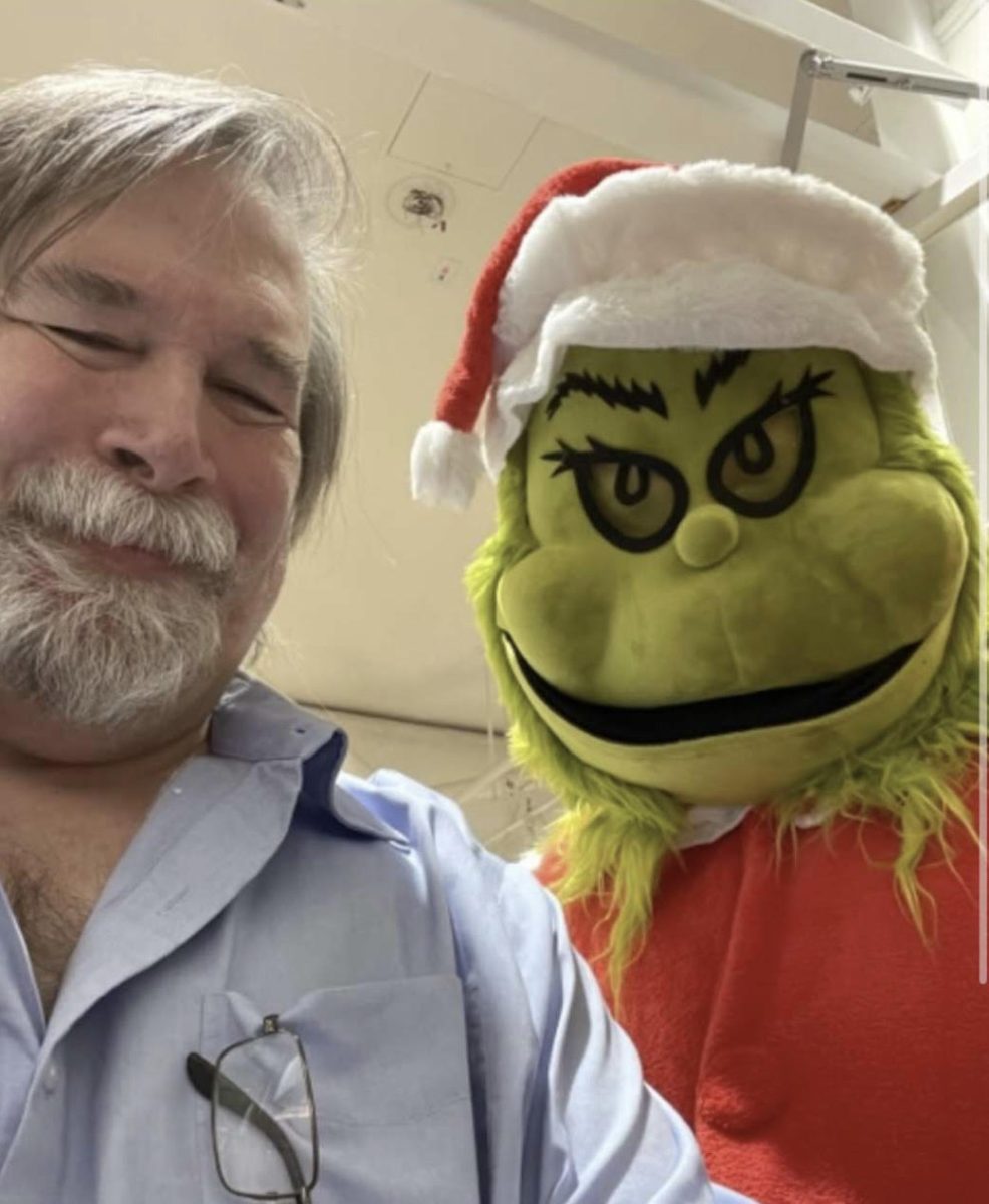 Social studies teacher Jefferey Benya takes a selfie with a student dressed as the Grinch to get in the Christmas spirit.