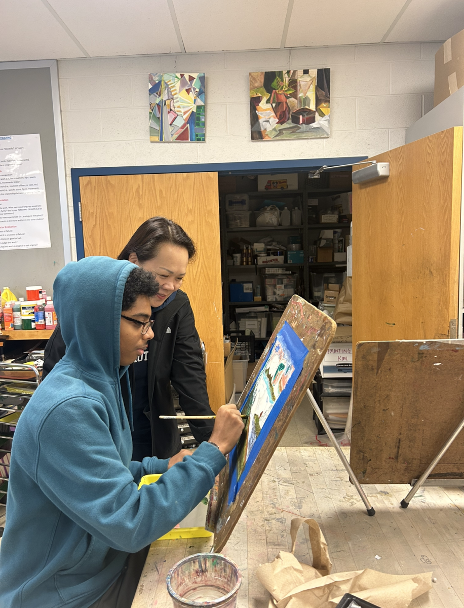 Art teacher Unsil Kim oversees freshman Bereket Kebede on his painting during class and provides helpful advice.
