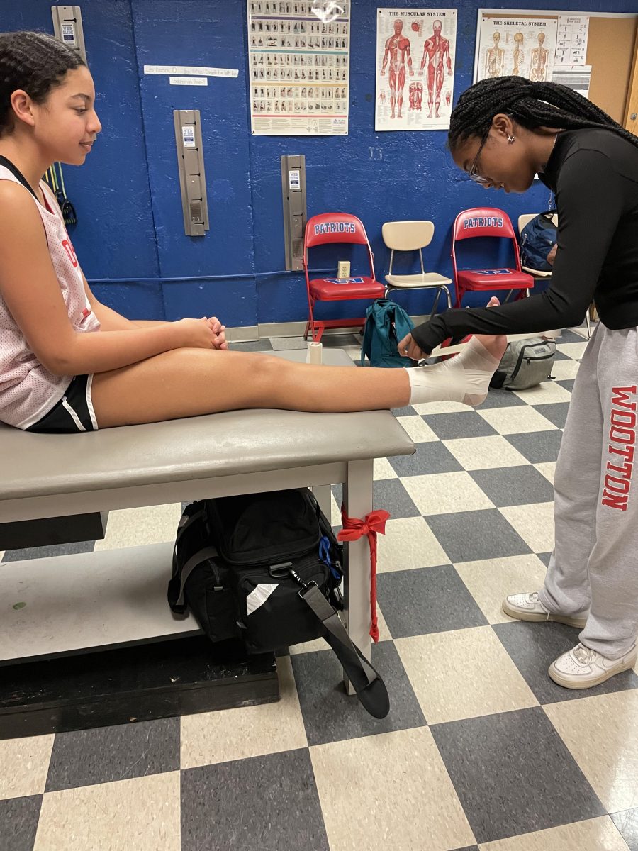 Junior intern Leanne Brown tapes freshman Malia Bellamys ankle in the athletic room as she prepares for basketball practice.
