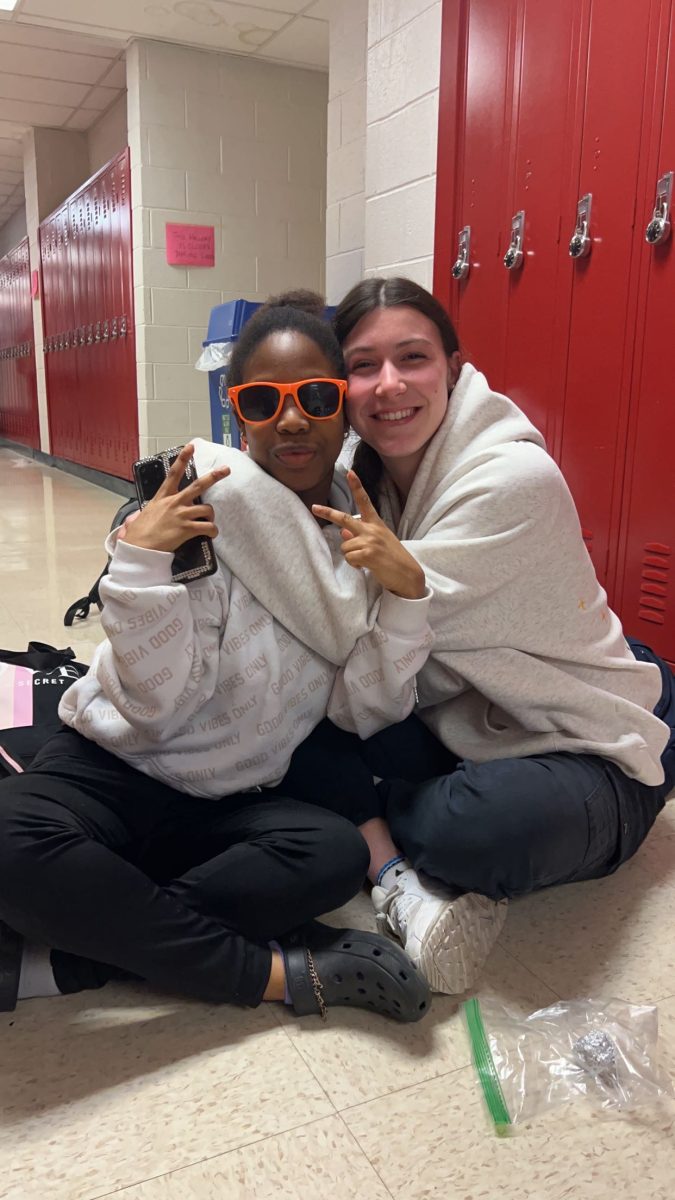 Sophomores Fanta Tarawallie and Abby Goozh hug in the science hallway during lunch. Physical touch like hugs generates positive mental health outcomes. Getting to spend time with friends really helps my mental health and makes me happy, Goozh said. 