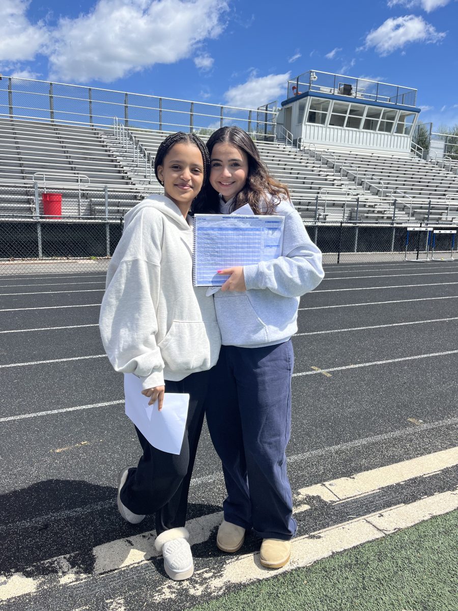 JV girls lacrosse managers, sophomores Ruth Bayou and Zoi Bourazani, prepare to keep score during a home game against Blake on Apr. 13. Their job also consists of helping the coach out with anything they need and taking care of social media,” Bourazani said.