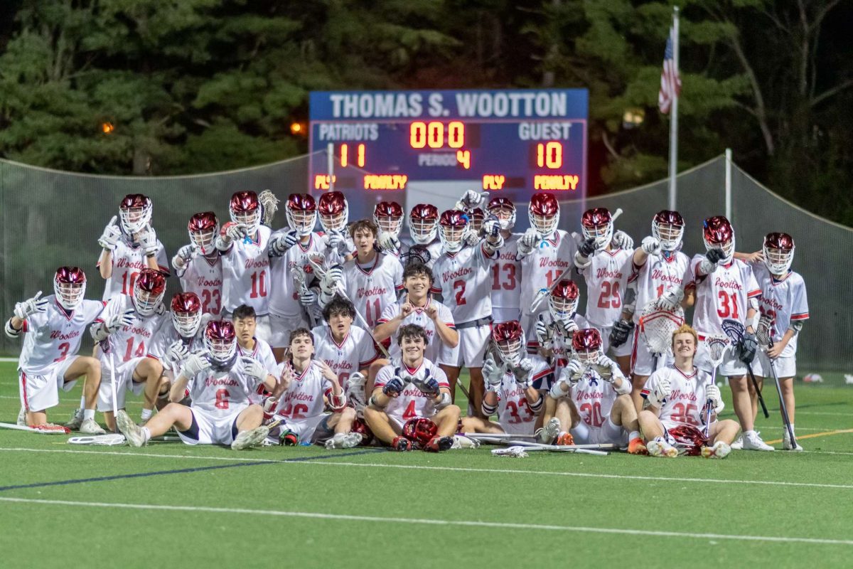Boys varsity lacrosse celebrates in front of the scoreboard after their 11-10 win against Rockville.