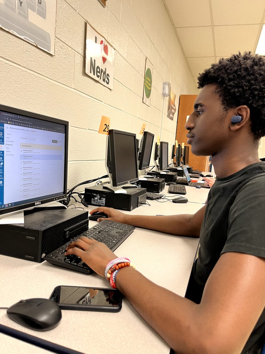 Sophomore Amad Sangare works on a Photoshop assignment in his eighth period website development class while listening to Your Love is King, by Sade.