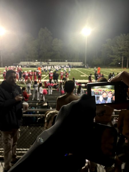 Junior Mia Coven takes photos on digital camera during the homecoming football game against Watkins Mill.