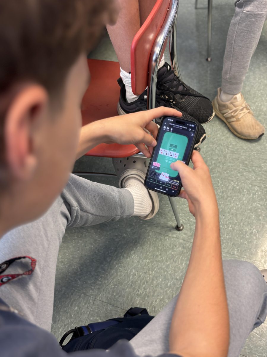 A student plays poker in class with friends. "I think poker is a really good way to socialize. Even though I'm playing it in class with my friends, I just want to have fun with them," a  junior who requested to remain anonymous said.