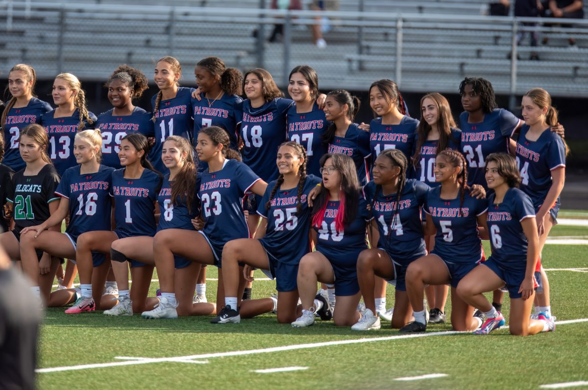 The varsity girls' flag football team lines up for pictures alongside five other teams at the opening ceremony of the  inaugural games on Sept. 5. The team defeated Clarksburg 14-13 that night.