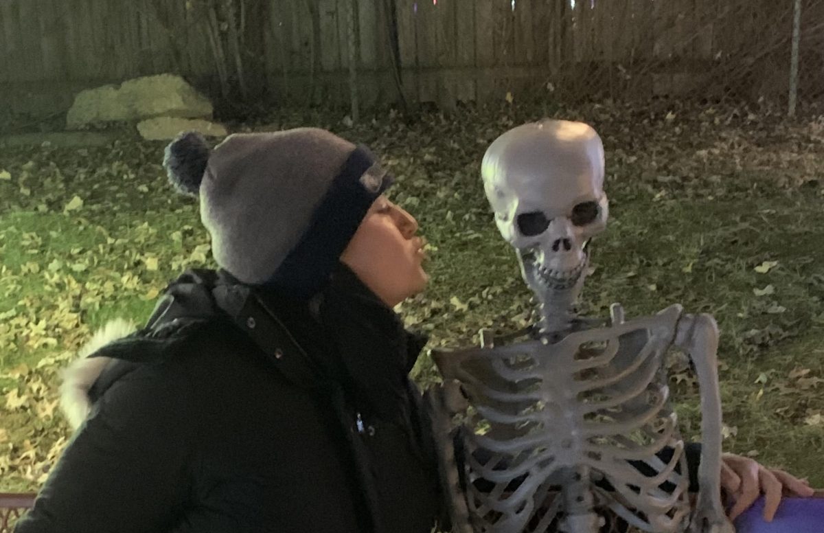 Senior Sid McCasland plays with a Halloween decoration of a skeleton. Decorations are a common tradition for homeowners to add flair to their property during the Halloween season. "I'm so excited for Halloween. Halloween is my favorite holiday," McCasland said.