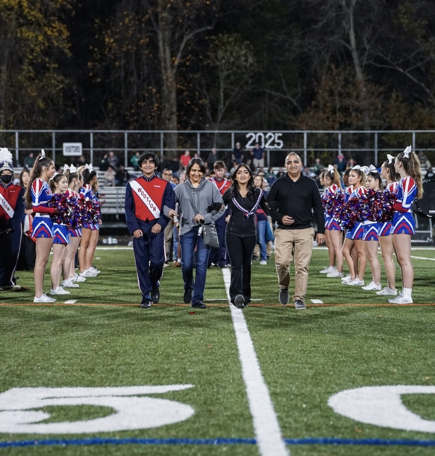 Senior Sana Majmudar walks for senior night with her parents and brother. This year concludes her third year of marching band as a color guard member. "I'm so grateful to everyone for such an amazing season," Majmudar said.