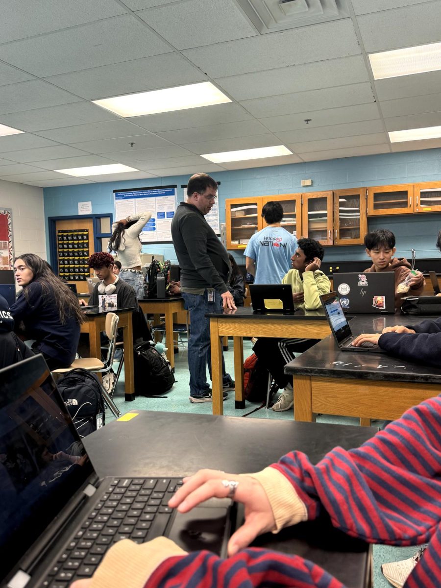 Science teacher Brett Bentley helps a student with their project in fourth period AP Research on Wednesday, Dec. 18.