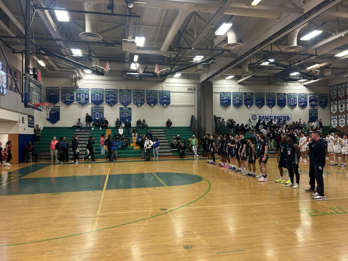 The boys' varsity basketball team stands for the National Anthem on a Dec. 20 matchup against Churchill. The Bulldogs physicality and fast-paced offense exposed the team’s struggles with turnovers and cold shooting, leading to a 60-47 defeat.