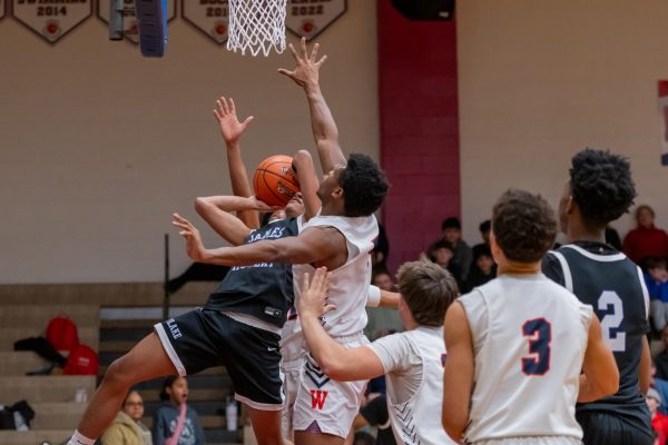 Junior Bryan Ngouzo goes up for the block in the boys' varsity basketball game against James Hubert Blake  on Friday, Feb. 21. "I am excited to see how far this team goes in playoffs. I have high hopes," Ngouzo said.