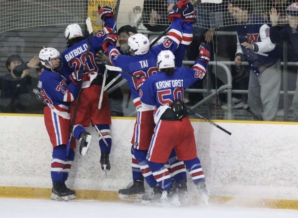 The hockey team celebrates after sophomore Evan Batbold scores a goal in rivalry game against Churchill on Feb. 7.