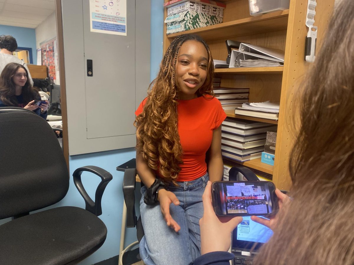 Junior Urielle Ngako shows her short film "#StudentsInYourFields" to junior Anna Nishnianidze on Mar. 14 in the back of the TV production room. While Nishnianidze watches the film, Ngako explains the creation process. "Urielle is extremely hardworking and perseverant, and she expresses these qualities on a day-to-day basis," Nishnianidze said.