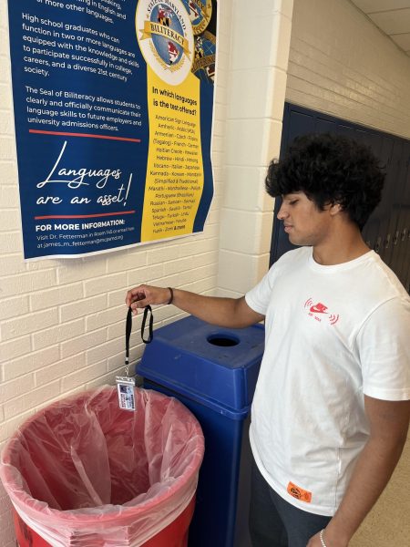 Junior Vishnu Varma dangles his student ID over the trash can in hopes of policy changes.