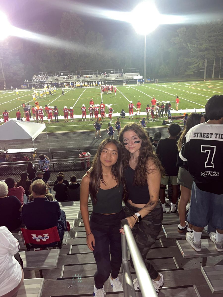 Freshman Hannah Yuan  and senior Maddie Zincke attend the blackout football game against Watkins Mill on Oct.18, 2024.