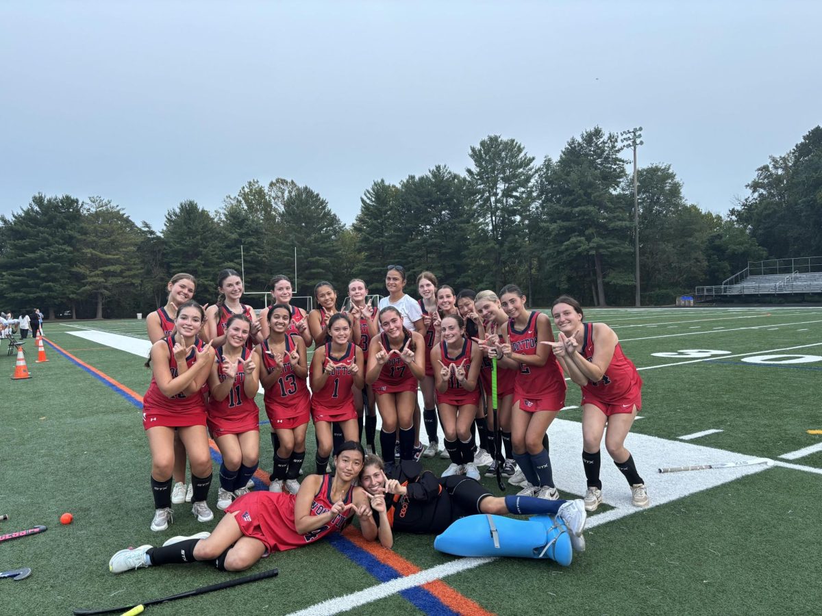 Varsity field hockey, led by coach Gina Britton, celebrates their first victory of the season against Clarksburg. “I really love the community we have within our team; practice is productive but always fun. Varsity field hockey is truly like a family,” junior defender Gabi Estrada said. Photo courtesy Wootton Field Hockey Instagram.