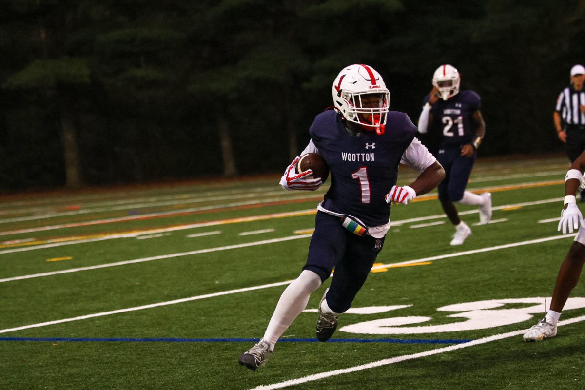 Senior football player Ashton Ingram carries the ball while running down the field in a game against Walter Johnson on Sept. 26. Photo by Keon Gray