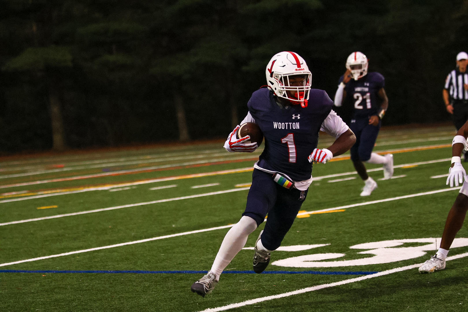 Senior football player Ashton Ingram carries the ball while running down the field in a game against Walter Johnson on Sept. 26. Photo by Keon Gray