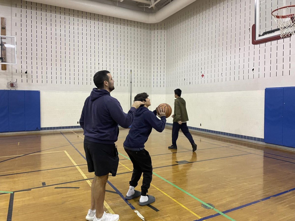 Physical education teacher Patrick Bernardo coaches freshman Danny Azoff's shooting form during their basketball unit.