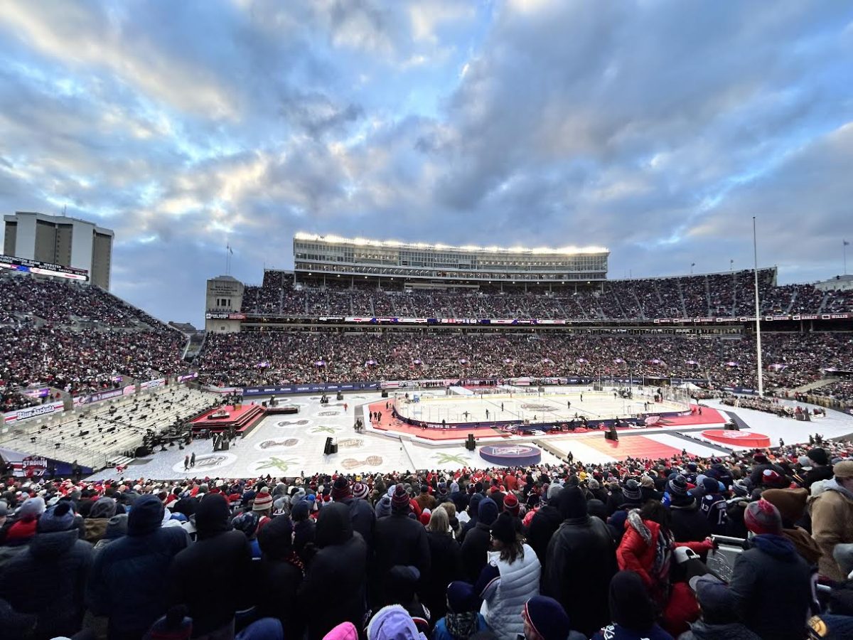 Under a vast evening sky and the glow of stadium floodlights, the Columbus Blue Jackets host the Detroit Red Wings in a historic outdoor clash. The massive crowd at Ohio Stadium created a sea of energy beneath the bright lights. "2025 Stadium Series 2025-03-01" by Phoenix-Five is licensed under CC BY-SA 4.0.