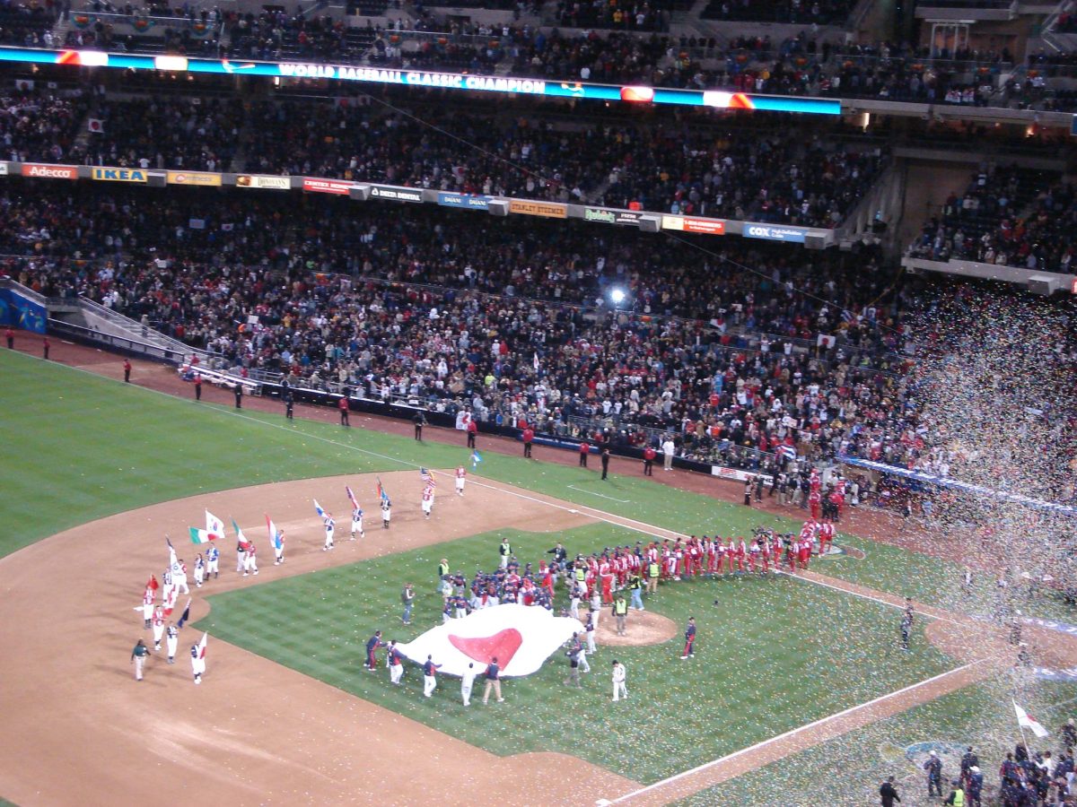 Team Japan celebrates its inaugural World Baseball Classic championship as they defeated Team Cuba 10-6. The players and coaches hold the Japanese flag in the middle of the diamond in celebration of their championship. By User ilovemypit on Flickr is licensed under CC BY 2.0.
