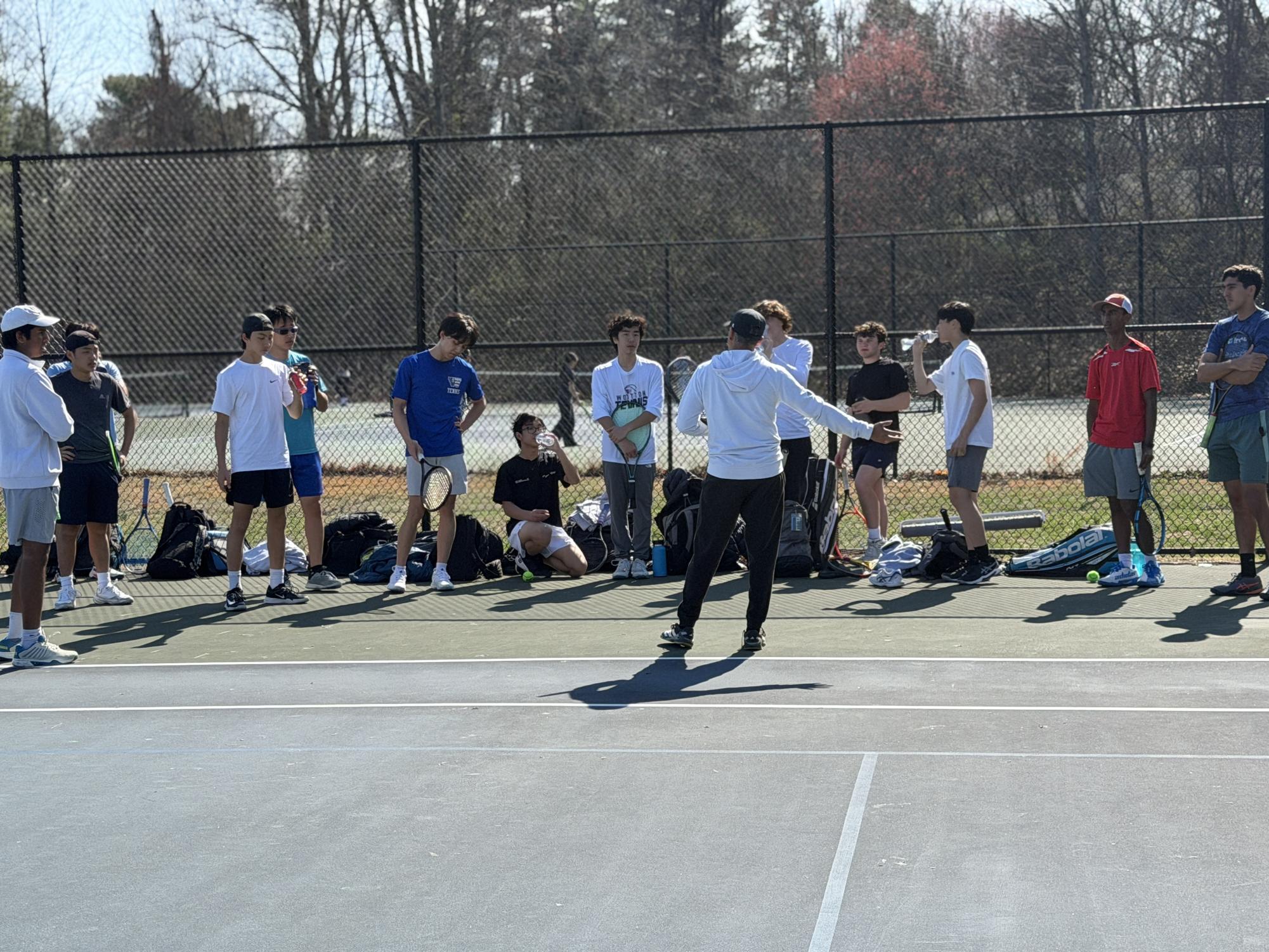 Boys' tennis Coach Nitin Deodhar gives a team talk during water break mid-way through the final March 18 practice before the first match the next day. “I believe that we can definitely win tomorrow,”  Deodhar said.