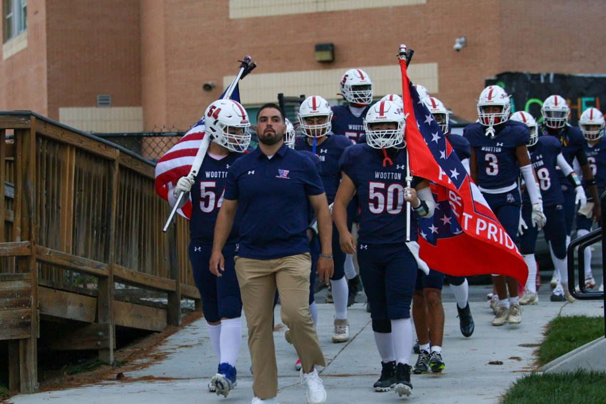 Varsity football head coach Patrick Bernardo leads the team onto the field against Richard Montgomery on Oct. 10, 2025. Photo by Keon Gray