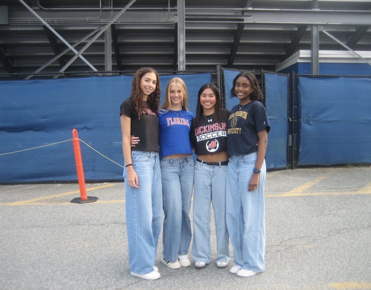 Seniors and best friends Maya Bellamy, Emory Scofield, Megan Lomotan and Helen Manolis (this writer) wear their college shirts to senior picnic on May 1. Bellamy will be playing lacrosse at Haverford College, Scofield will be studying journalism at the University of Florida, Lomotan will be playing soccer at Dickinson College and Manolis will be studying journalism at the George Washington University next year. Photo courtesy Megan Lomotan