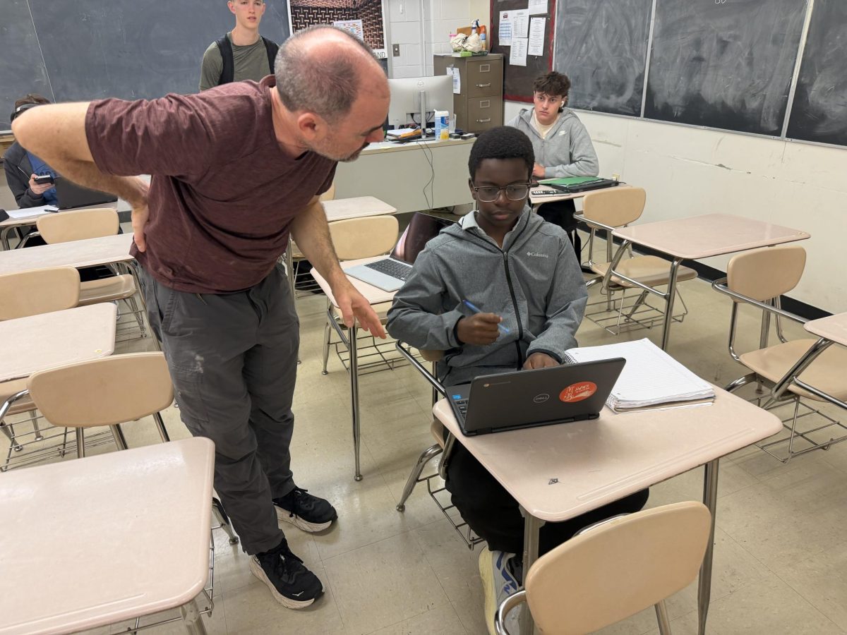 New math teacher David McMahon helps students better understand the classwork after a difficult teacher transition from the previous math teacher, Albert Ticona, in early April. McMahon helps one of his students during homeroom on May 21.
