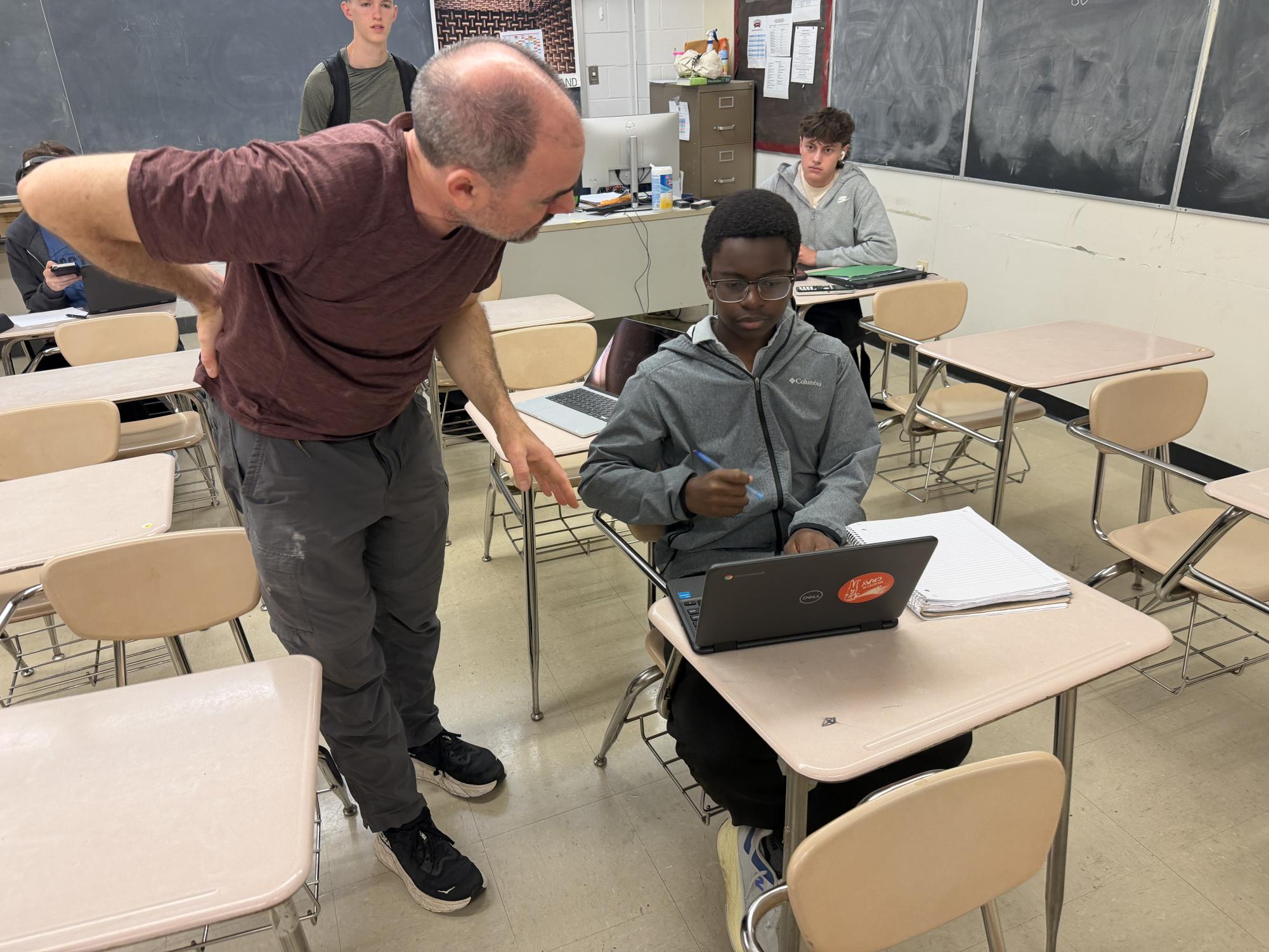 New math teacher David McMahon helps students better understand the classwork after a difficult teacher transition from the previous math teacher, Albert Ticona, in early April. McMahon helps one of his students during homeroom on May 21.
